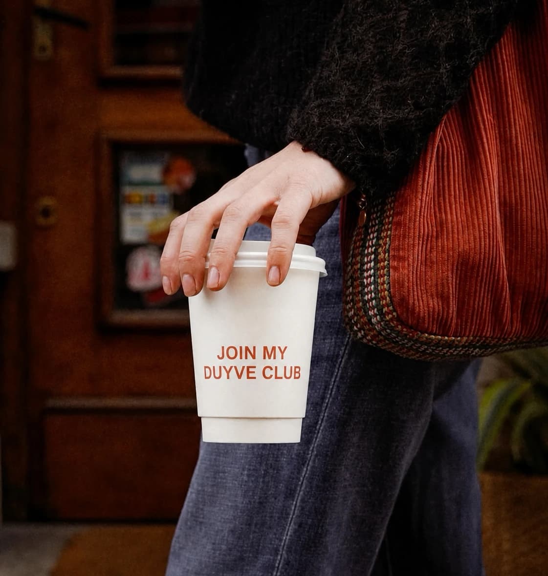 Person holding a coffee cup inviting people to join a Duyve club